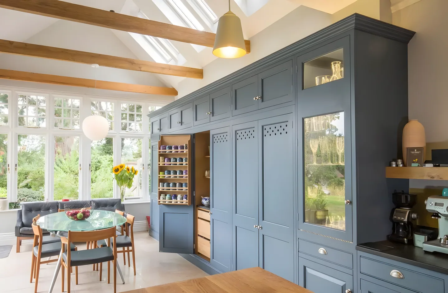 A tall slate blue painted dresser wall with glazed doors and a larder