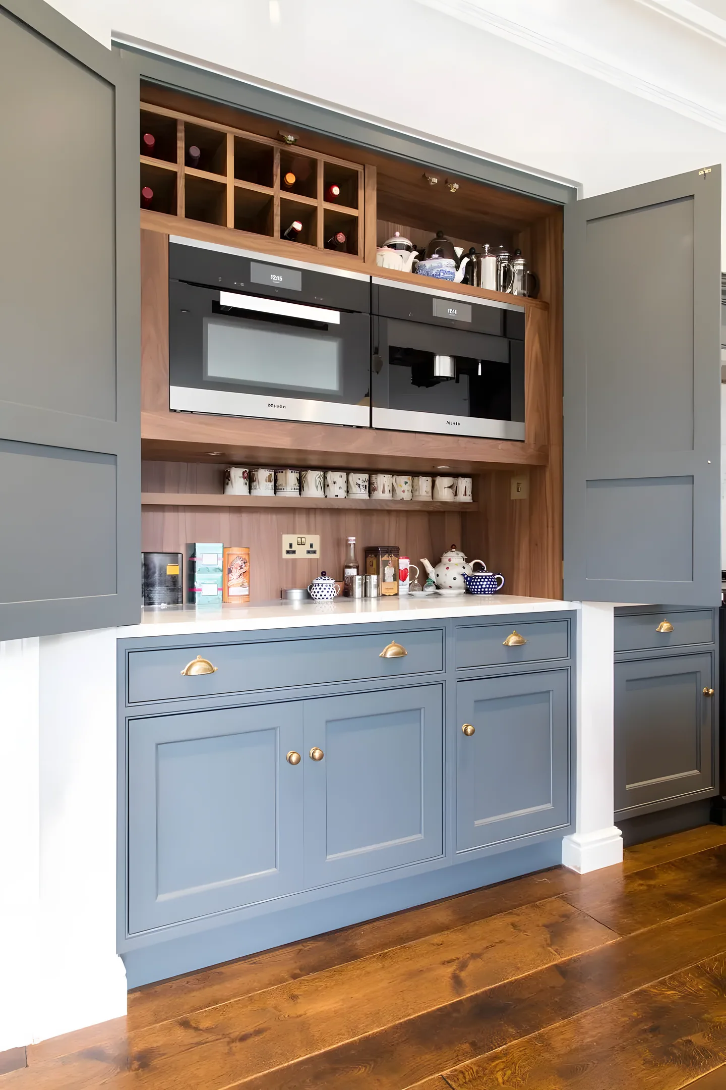 A blue painted coffee station with oak shelving and a drawer open