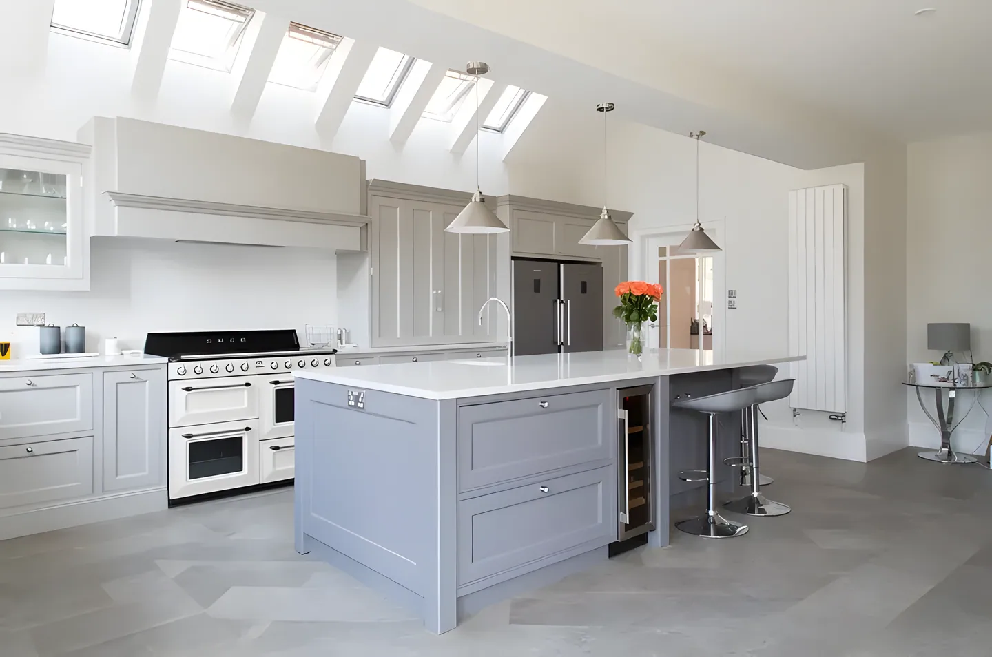 A dove grey painted island with a wine cooler and pendant lights