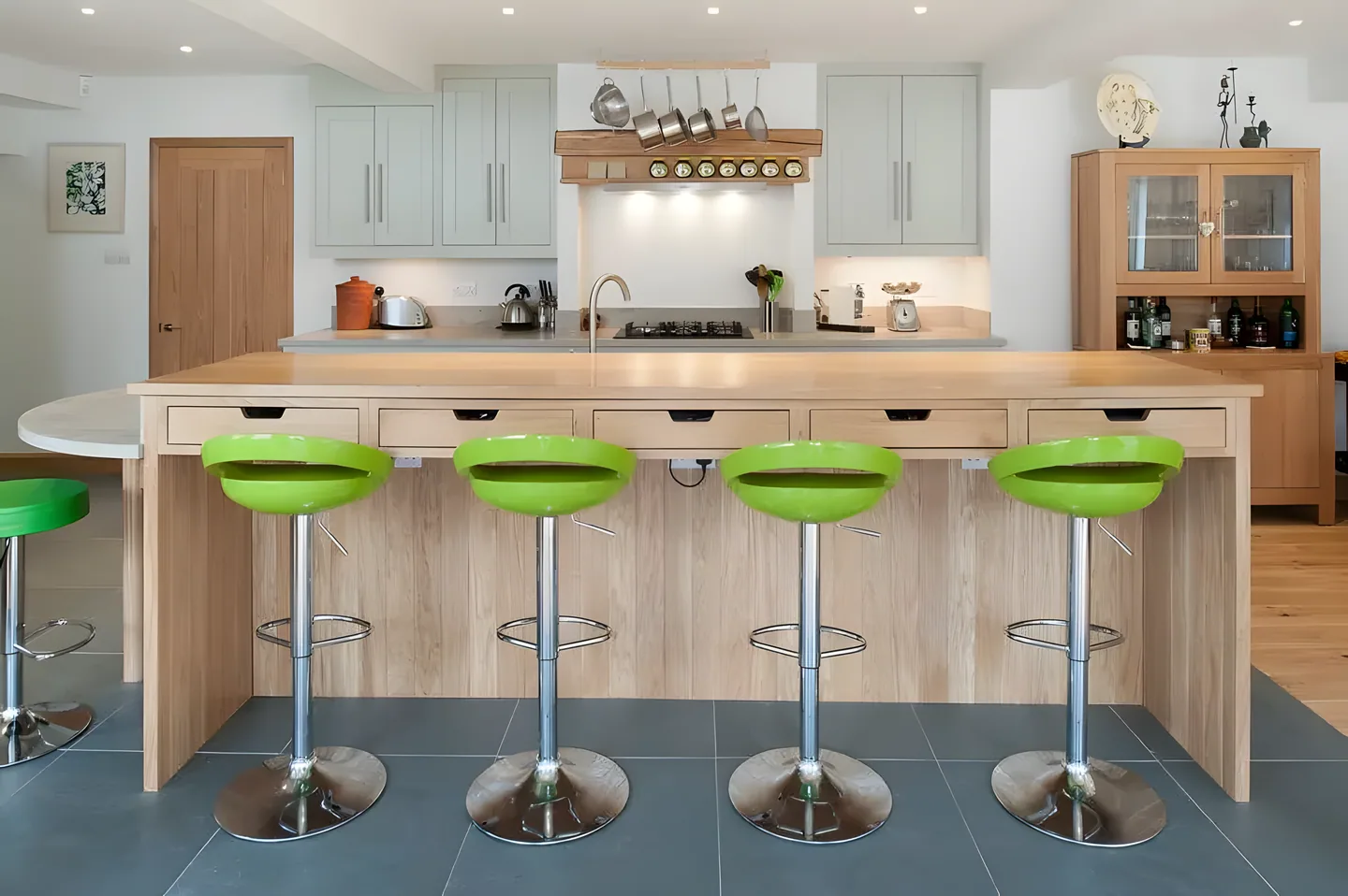 An oak breakfast bar with green stools
