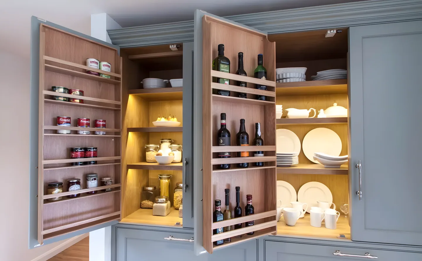 A wide pantry run of painted cabinets with oak shelving and drawers