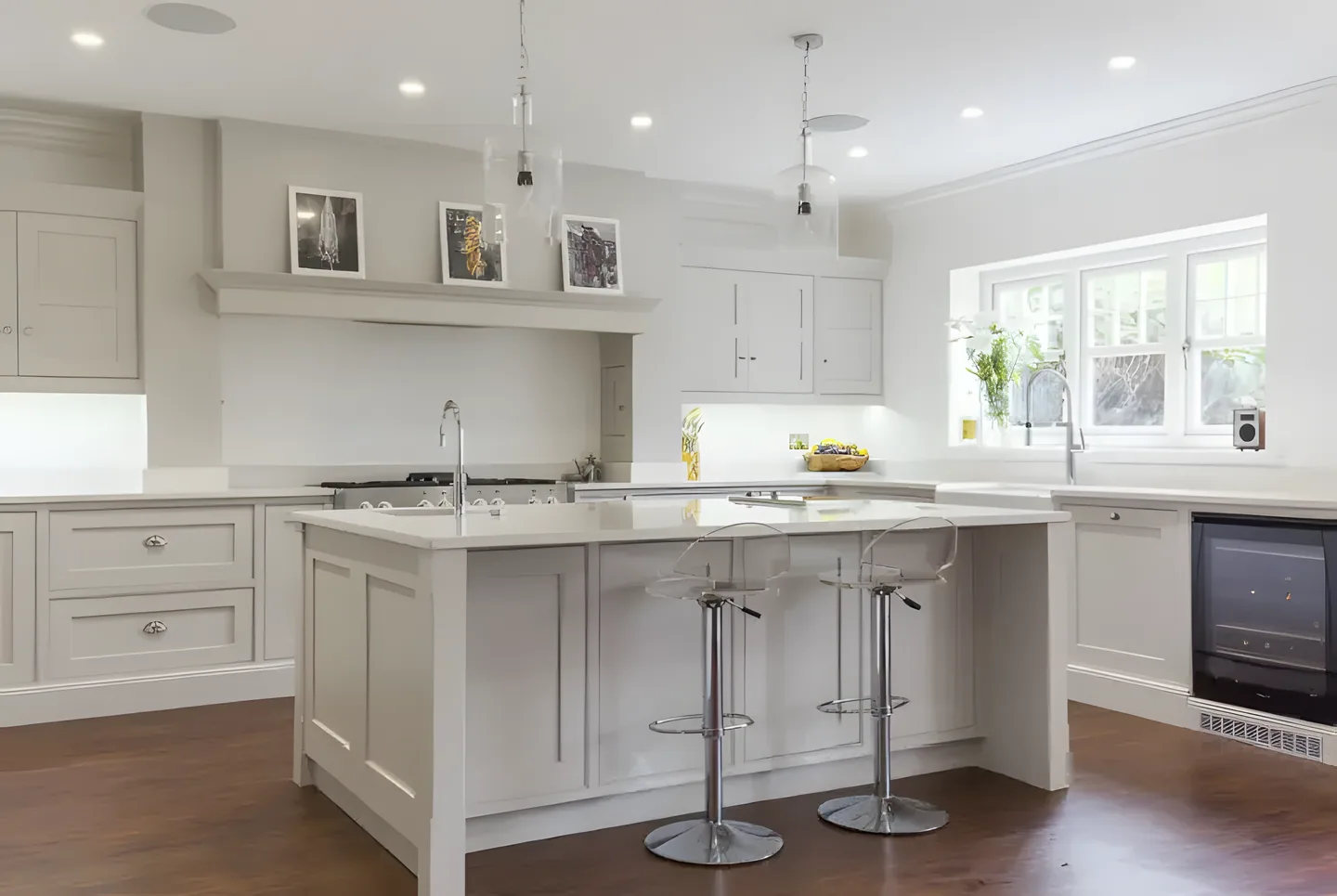 A pale stone and cream painted kitchen with a large island and stools